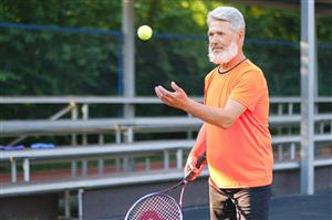 Senior Man Serving Tennis Ball